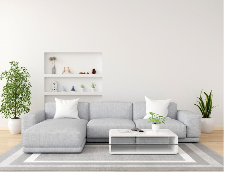 Como Escolher o Tapete Ideal para Sua Casa 2 como escolher o tapete, imagem mostra uma sala com paredes brancas, sofa cinza e tapete cinza com bordas branca e cinza, mesa de centro branca