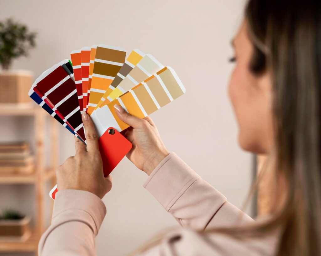As Cores De Tinta Do Ano 2025 1 cores de tinta do ano 2025, imagem mostra uma mulher de costas mostrando nas mãos uma paleta de cores de tintas coloridas
