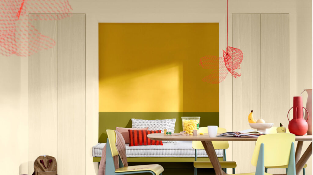 As Cores De Tinta Do Ano 2025 2 cores de tinta do ano 2025, imagem mostra um sofá e uma mesa em frente a uma parede pintada com a cor amarelo vibrante