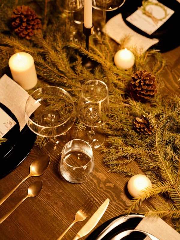 Decorando Para Natal: Um Convite à Magia da Decoração ✨️ 2 decorando-para-natal, imagem mostra mesa de madeira decorada para ceia de natal, com ramos de folhas decorando a mesa, taças e velas
