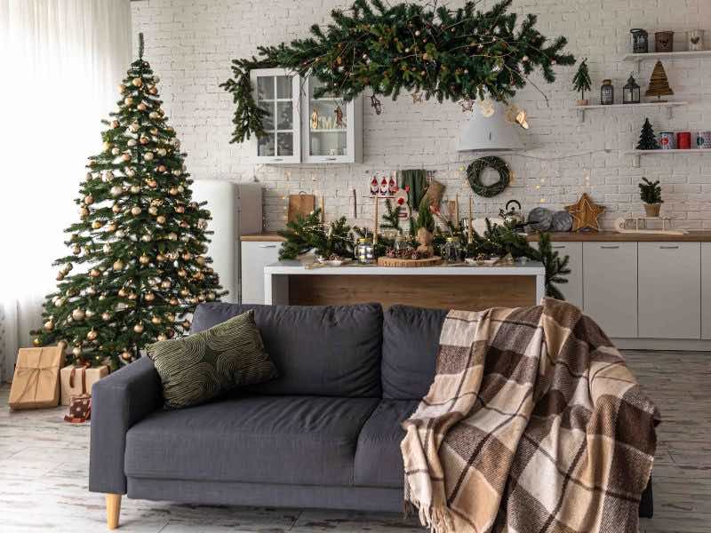Decorando Para Natal: Um Convite à Magia da Decoração ✨️ 1 decorando para natal, imagem mostra uma sala com sofa cinza, prateleiras e moveis atras dele, e uma arvore de natal ao lado