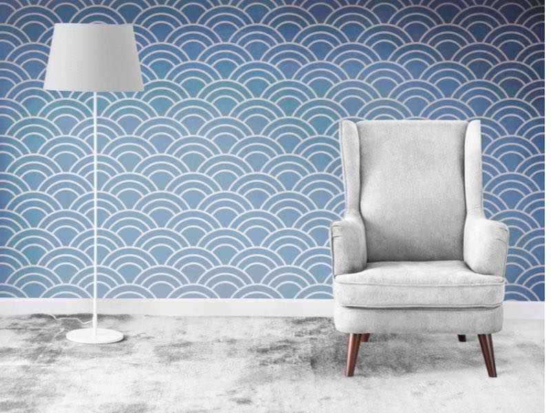 Como Escolher Papel de Parede Ideal para a Sala de Estar 1 escolher papel de parede, imagem mostra uma parede com papel de parede azul e desenhos geometricos brancos, na frente desta parede ha uma poltrona cinza e uma luminaria de piso